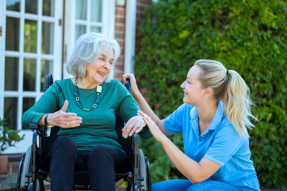 Elderly female in long term nursing care facility supported by a staff